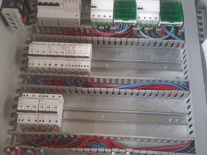 Armoire électrique en cours de montage : disjoncteurs, rails et câblage repéré